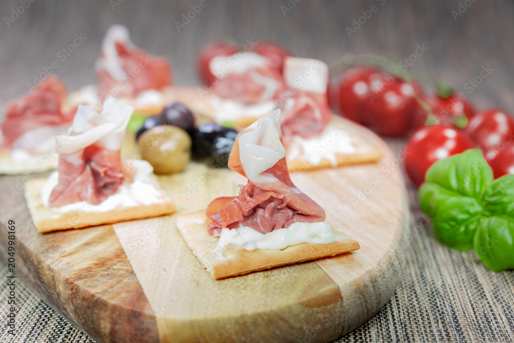 An appetizer of Italian ham, artisan stracchino and olives from Puglia (Italy). It is a very tasty typical appetizer.