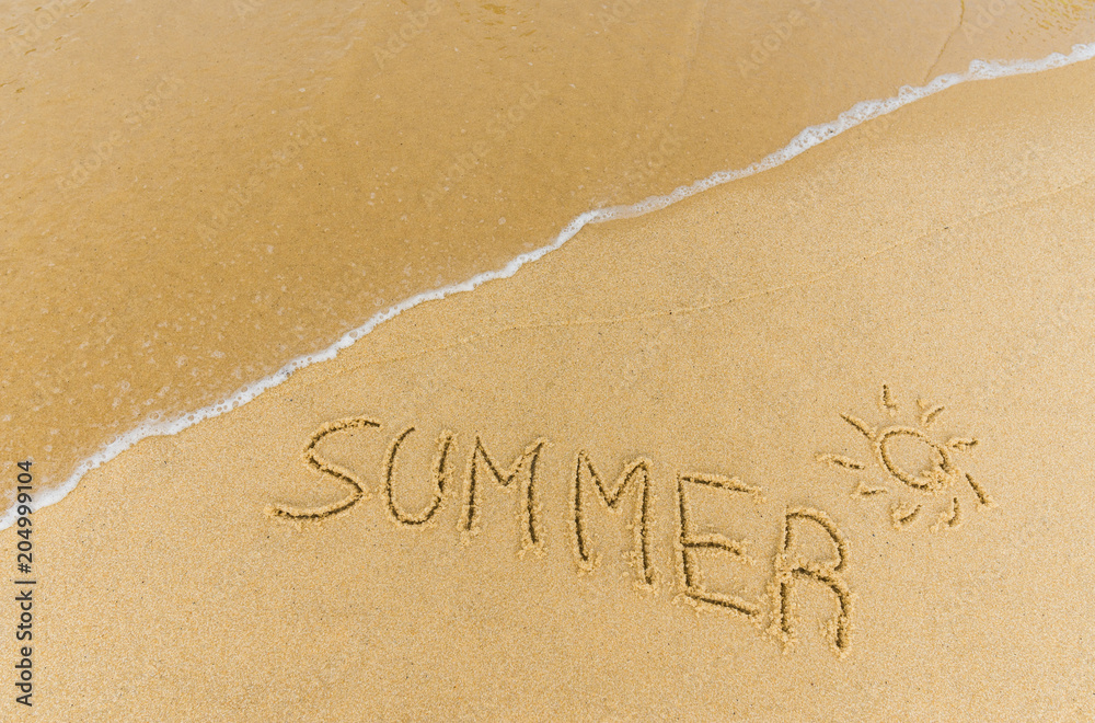 Fototapeta premium Ocean sea waves on the beach in a resort city running over the caption summer written on the sand. Concept of summer, holidays, vacation, travel, and beach