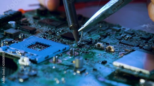 electronic renovation in repair shop. technician soldering motherboard photo