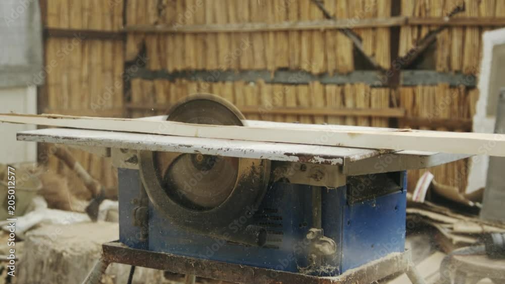 Slow motion shot of senior man sawing wood on the machine with a circular saw in his workshop Slow motion shot of senior man sawing wood on the machine with a circular saw in his workshop