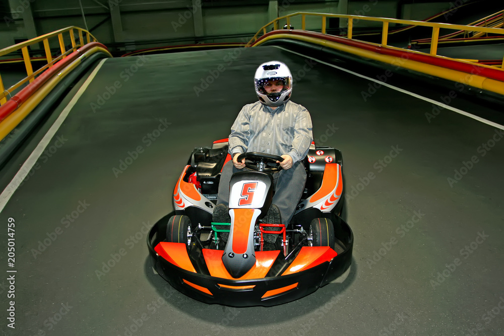 a man in helmet in the go-kart on the karting-track indoors