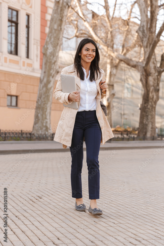 Delighted young woman dressed in autumn coat