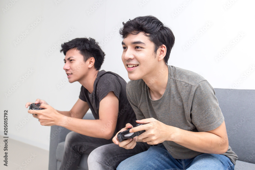 Asian man fun playing video games console with his girlfriend