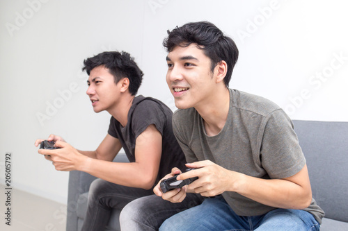 Attractive asian man playing videogames on tv with friend. People play game with happy emotion togeyher. People lifestyle concept. photo