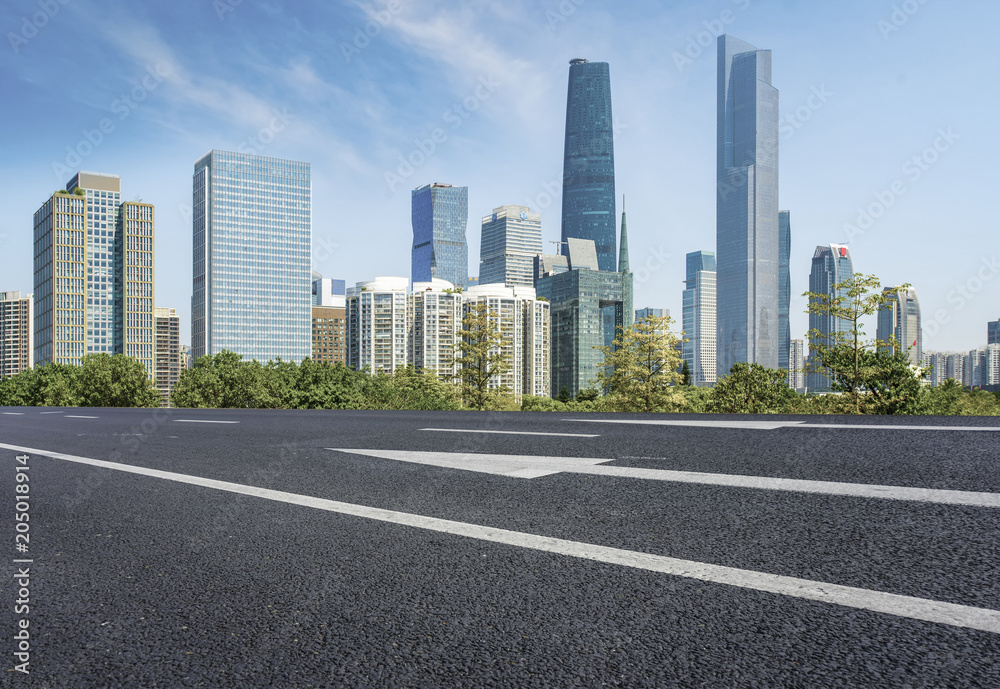 The empty asphalt road is built along modern commercial buildings in China's cities.