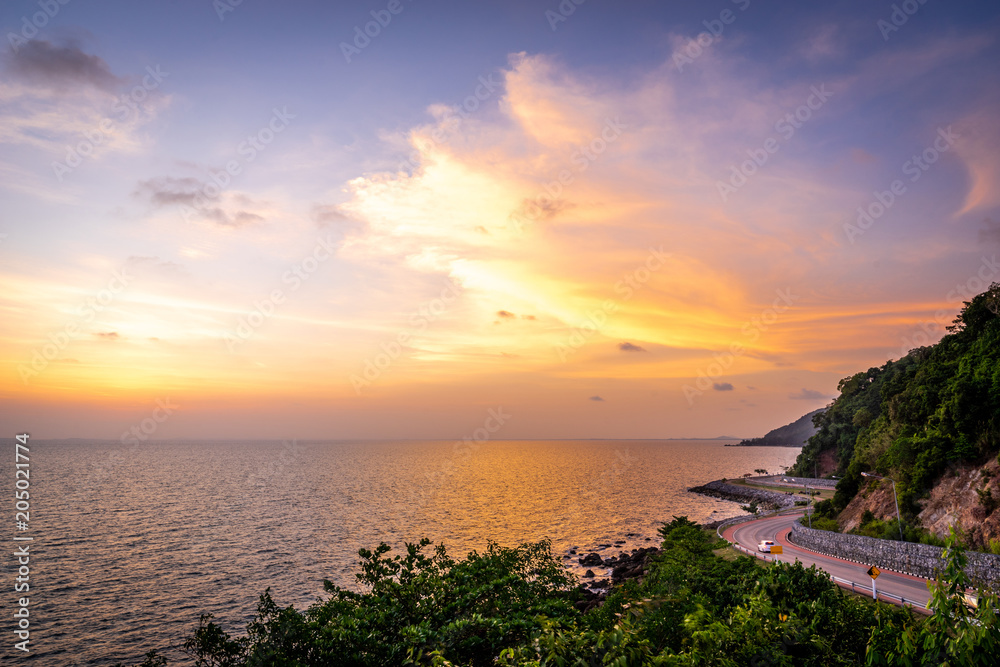 The seaside road adjacent to the mountain at sunset on the east side of Thailand.