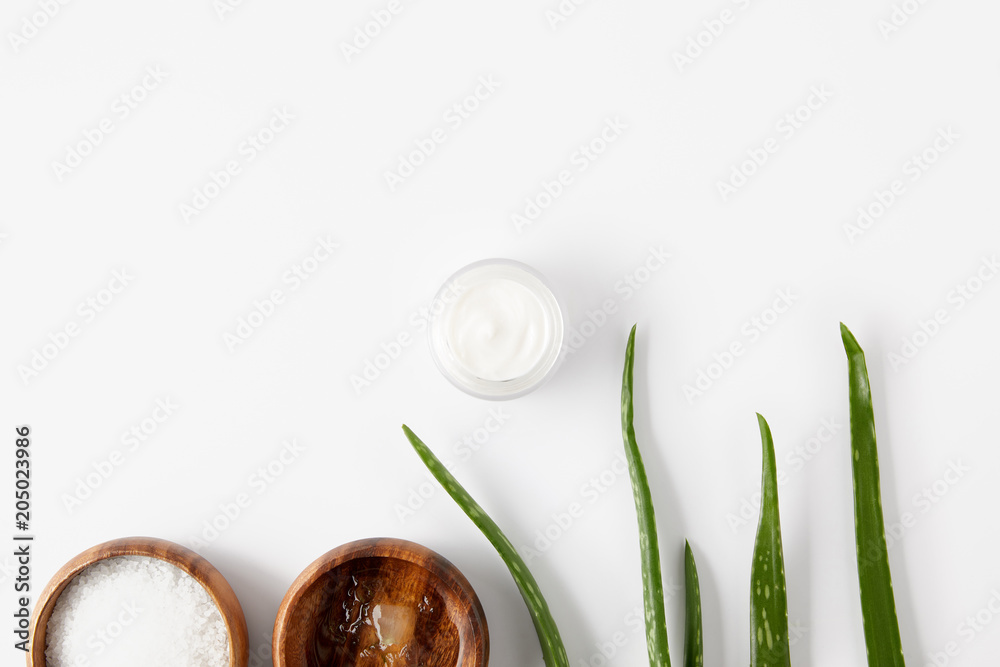 elevated view of two wooden bowls with aloe vera juice and salt, organic cream in container and aloe vera leaves elevated view of two wooden bowls with aloe vera juice and salt, organic cream in container and aloe vera leaves