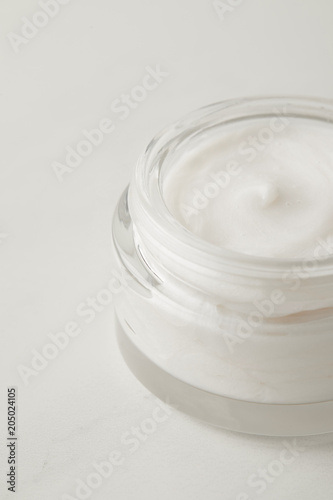 close up view of organic cream in container on white surface