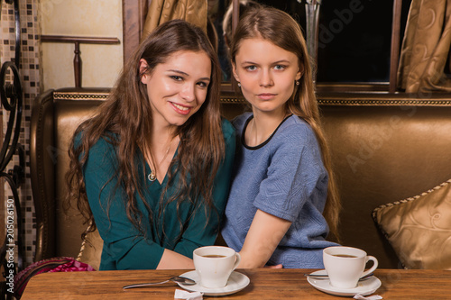 Two happy women drinking coffee in cafe