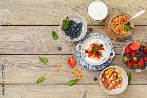 Bowl of homemade granola with yogurt and fresh berries on wooden background