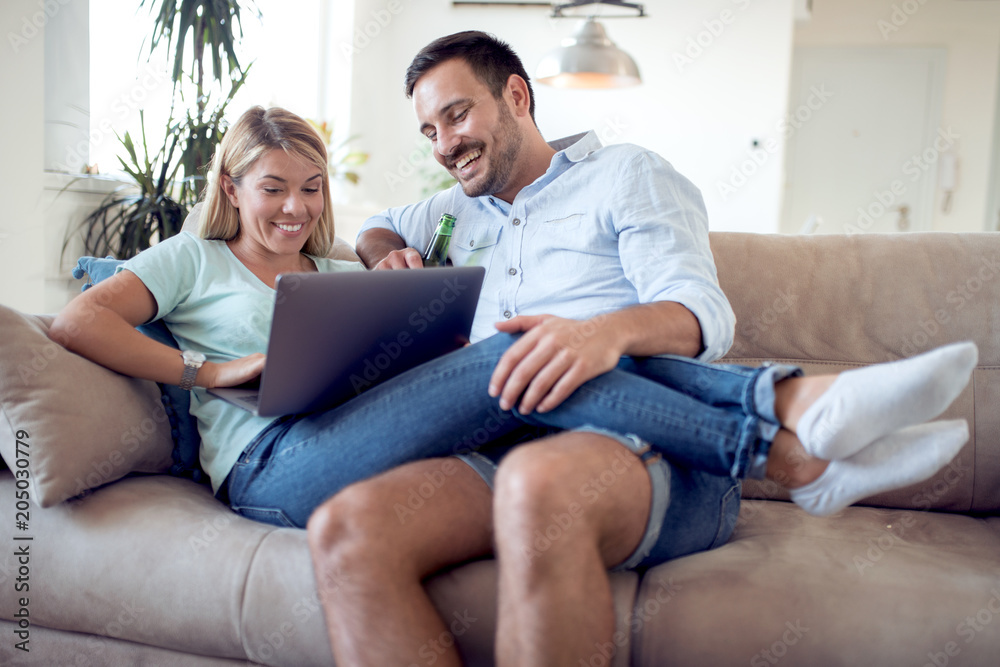 Young couple sitting in the living room and using laptop