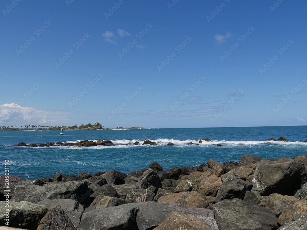 Boulders of stones piled right next to the blue waters at the walkway of Fort El Morro in Old San Juan, Puerto Rico.  