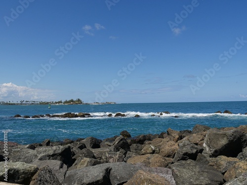 Boulders of stones piled right next to the blue waters at the walkway of Fort El Morro in Old San Juan, Puerto Rico. 