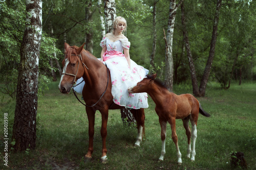 Beautiful woman in a retro dress is sitting on a horse.