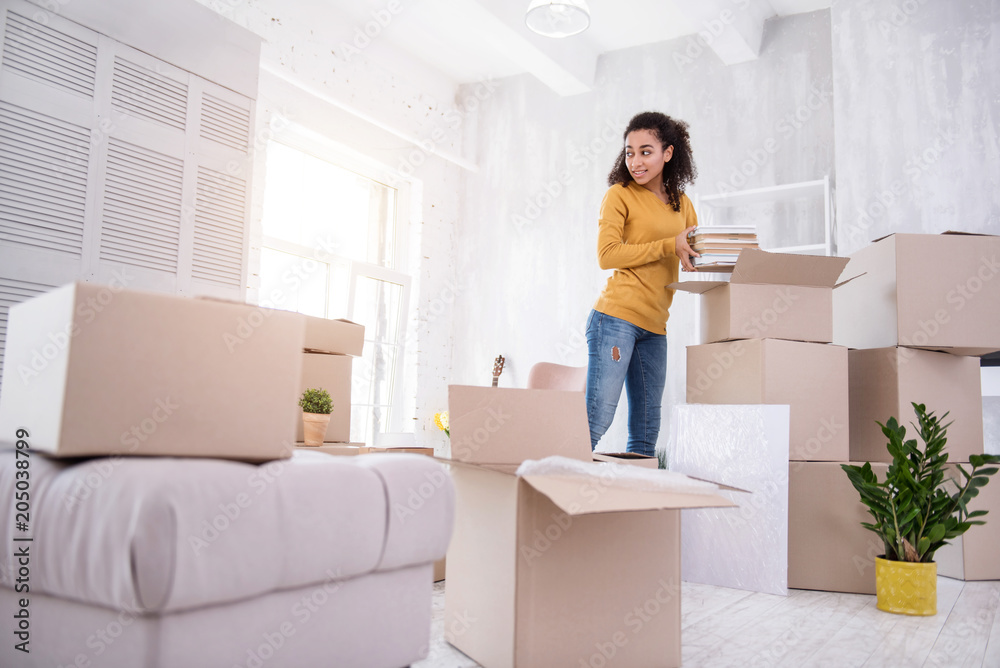 Bye dorm. Beautiful curly-haired girl packing books into the box while preparing to move out of the dormitory Bye dorm. Beautiful curly-haired girl packing books into the box while preparing to move out of the dormitory