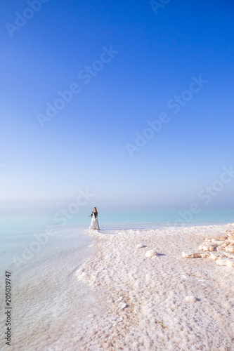 Blonde young woman in a long skirt on the shore of the dead sea. Jordan