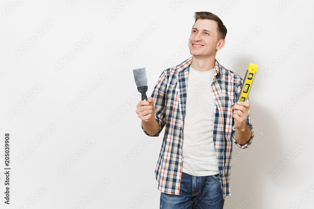 Young smiling man holding putty knife and building bubble spirit level and looking aside on copy space isolated on white background. Instruments for renovation apartment room. Repair home concept. Young smiling man holding putty knife and building bubble spirit level and looking aside on copy space isolated on white background. Instruments for renovation apartment room. Repair home concept.