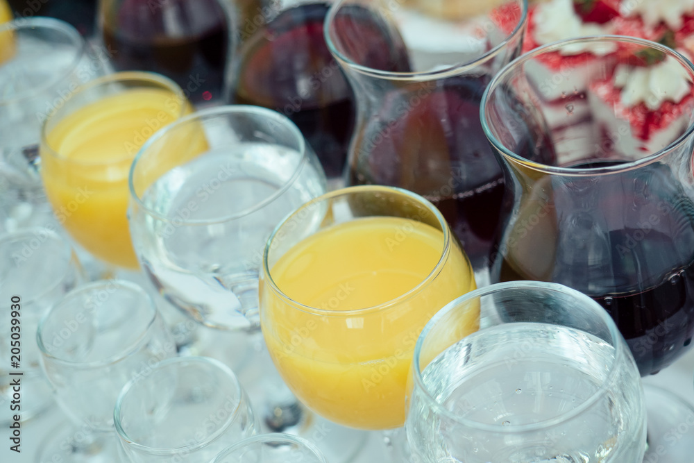 glasses with red wine, orange juice and water are on the banquet table glasses with red wine, orange juice and water are on the banquet table