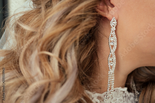 Earrings with rhinestones in the bride's ear with a beautiful hairdo