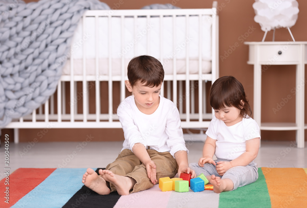 Fototapeta premium Cute little boy playing with his baby sister at home