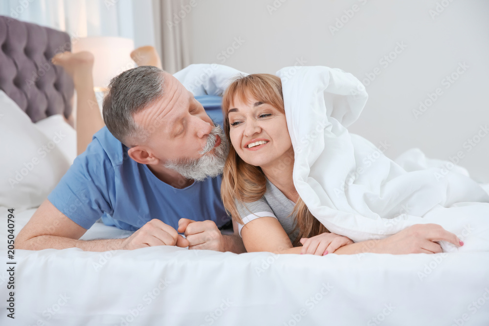 Mature couple together under blanket in bed at home Mature couple together under blanket in bed at home