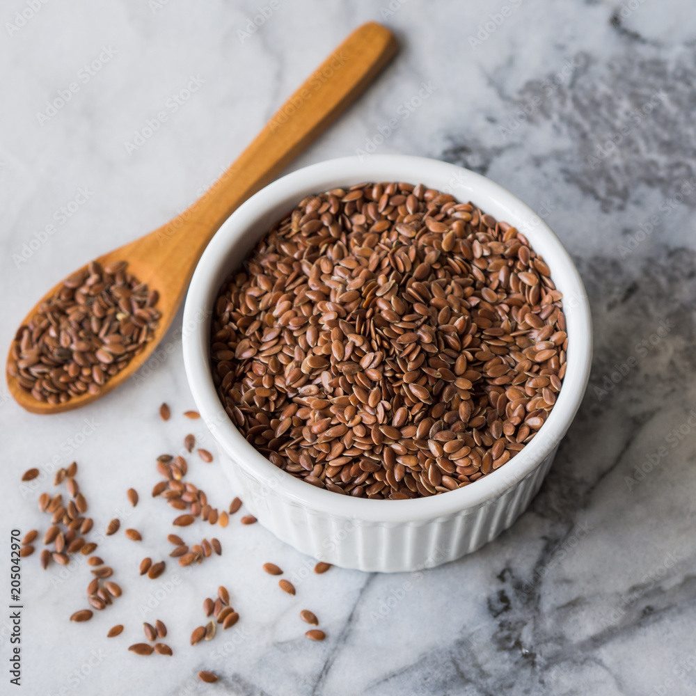 Flax seeds in white ramekin on marble board Flax seeds in white ramekin on marble board