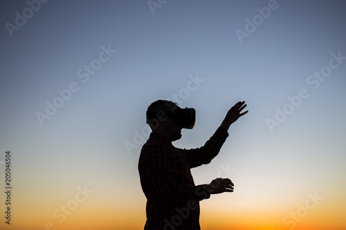 Man wearing virtual reality glasses on sky background