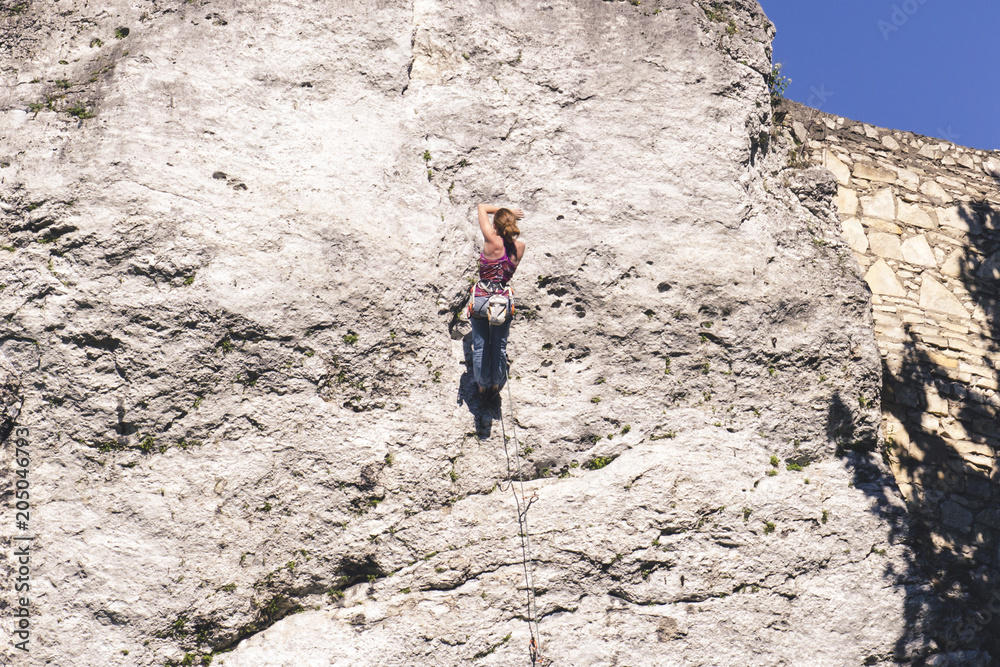 Young girl climber resting while scrambling on a steep rock