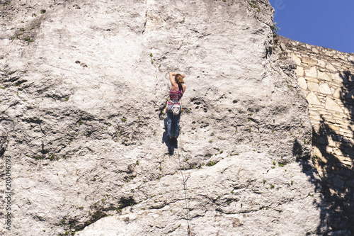 Young girl climber resting while scrambling on a steep rock