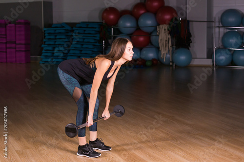 Muscular young fitness woman doing deadlift exercise in gym