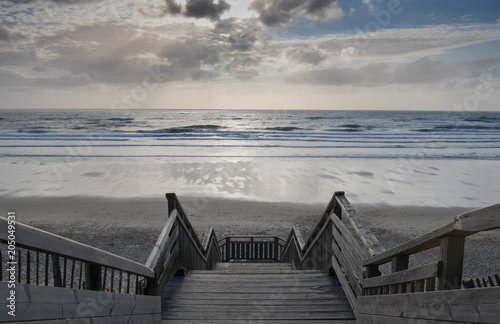 scenic biscarrosse beach in sunset with clouds and wooden footpath stairs, france photo