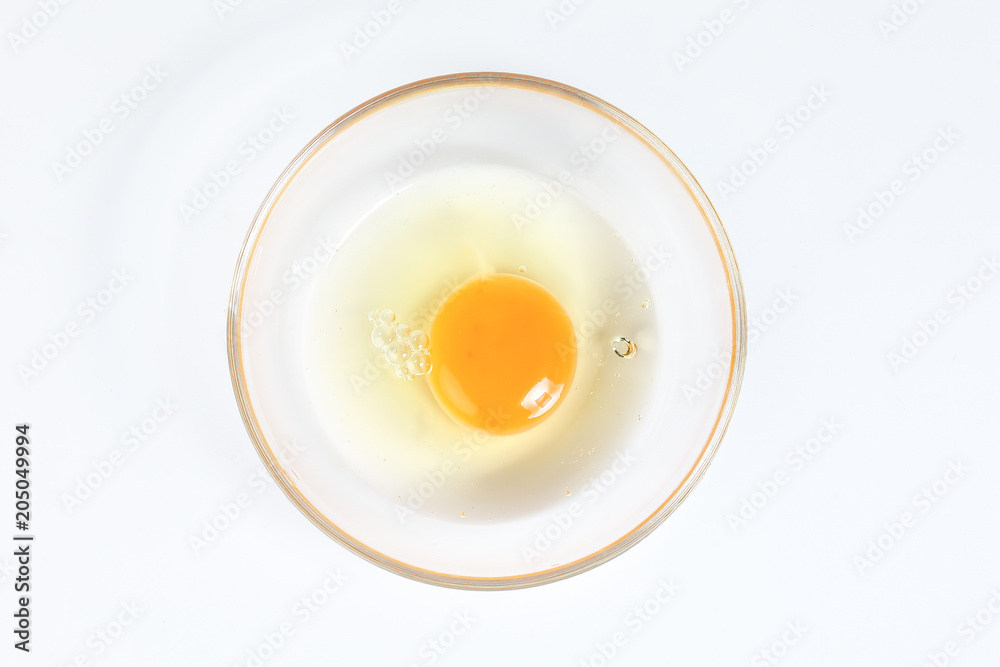 Raw Egg Yolk and white liquid in transparent glass bowl white background Raw Egg Yolk and white liquid in transparent glass bowl white background