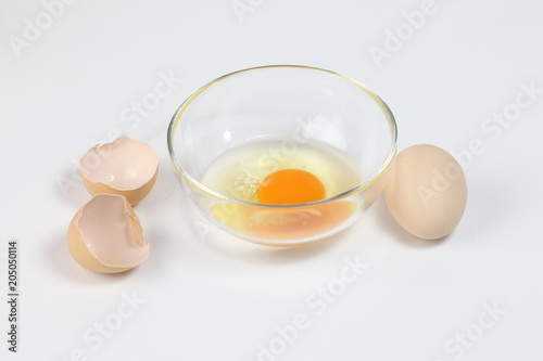 Raw Egg Yolk and white liquid in transparent glass bowl eggshell white background