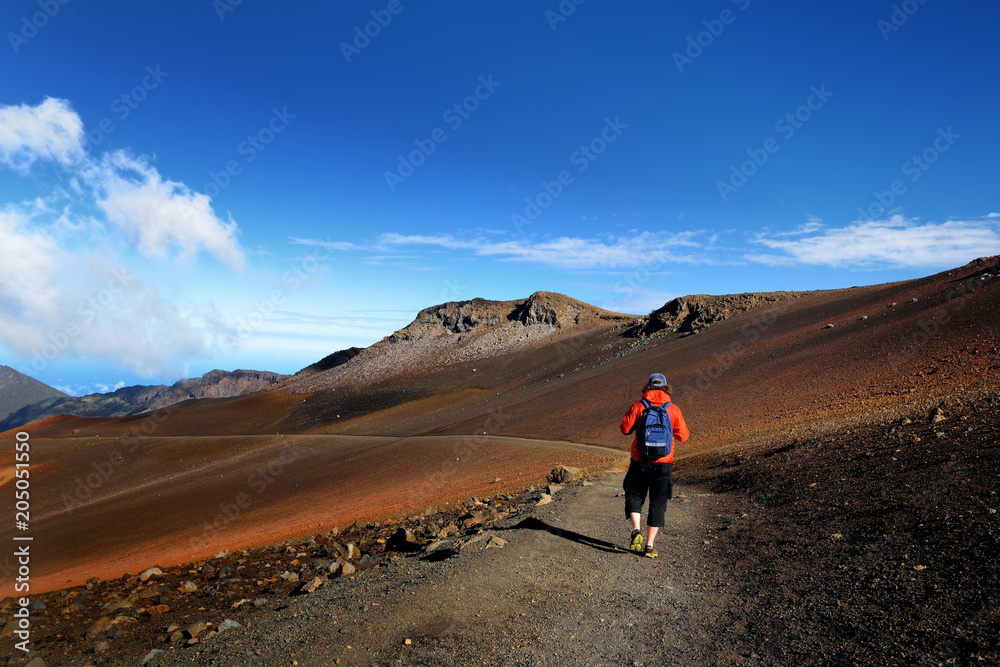 Tourist hiking in Haleakala volcano crater on the Sliding Sands trail. Beautiful view of the crater floor and the cinder cones below. Maui, Hawaii