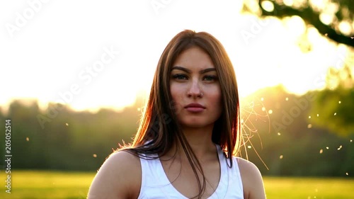 Young beautiful woman listening music at park while running. Portrait of smiling sporty girl with earphone looking at camera at park in autumn. Woman athlete looking at camera during winter sunset. photo