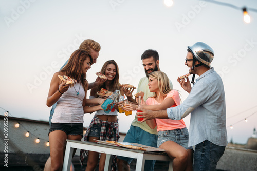 Group of young people sitting around and eating pizza