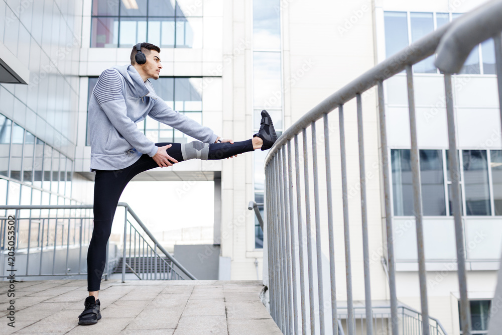 The young man is engaged in sports in the city. Warm-up before training in the morning. The young man is engaged in sports in the city. Warm-up before training in the morning.