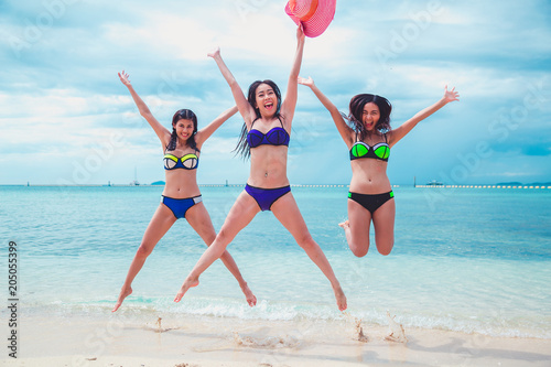 Beautiful asian teenage friends jumping on the beach