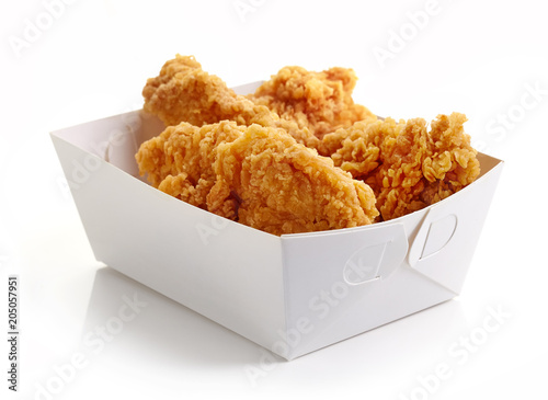 Fried breaded chicken fillet in white cardboard box isolated