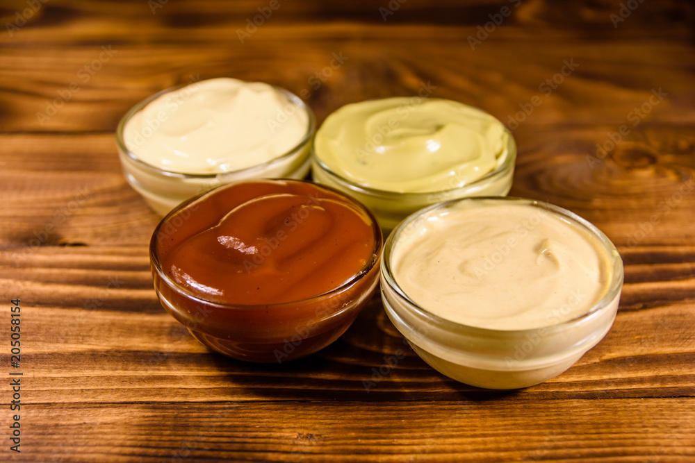 Different sauces in glass bowls on wooden table Different sauces in glass bowls on wooden table