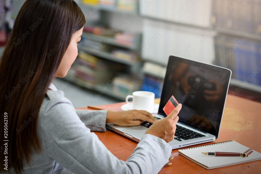 Asian business women pay for purchases using credit cards. During a laptop computer in the office. Finance, Banking and Technology Concepts.