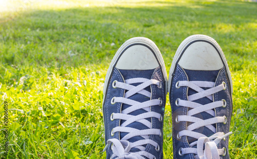 Youth sneakers, shoes on green grass during sunny serene summer day, Blue classic sneakers on green grass in the garden.
