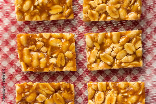 Candy with peanut: Pe de Moleque in Brazil and Chikki in India. Sweet food of Festa Junina, a typical brazilian party. Snacks on red plaid table. photo