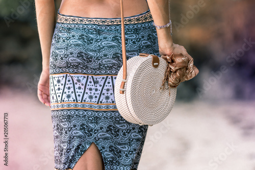 Woman hands with fashionable stylish rattan bag outside. Tropical island of Bali, Indonesia. Rattan and silk. photo