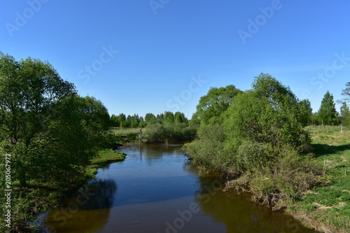 landscape flowing river  steep banks  green trees  blue sky