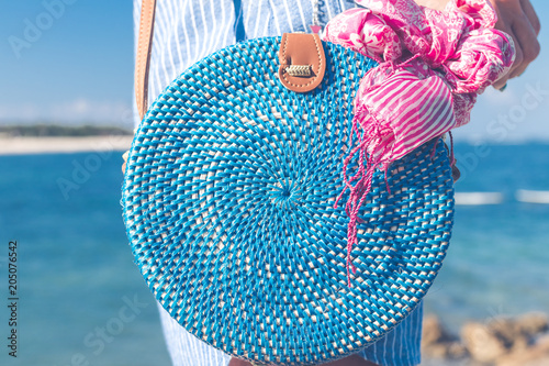 Woman with fashionable stylish rattan bag outside. Tropical island of Bali, Indonesia. Rattan and silk. photo