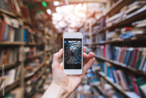 Human hand makes a photograph of a public library on a smartphone camera. Smartphone with library on screen.