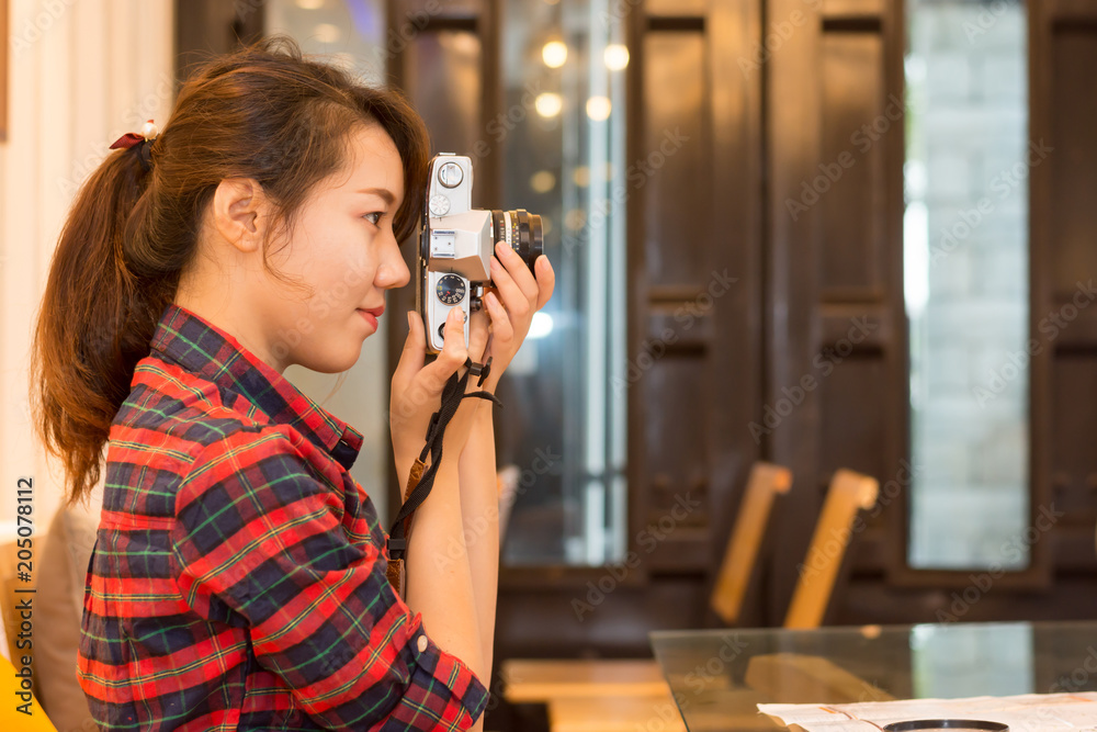 The girl is taking a photo with an ancient camera in her home.