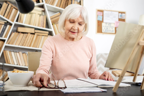 Lifetime learner. Focused senior woman studying while staring down photo