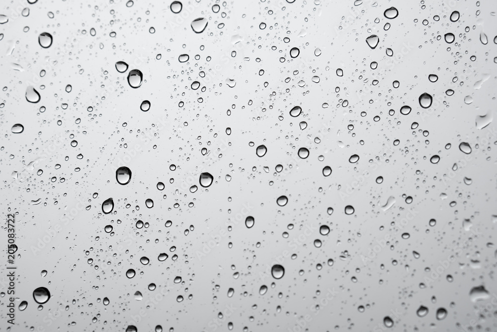 texture of rain drops on window glass over blur and cloudy sky background 